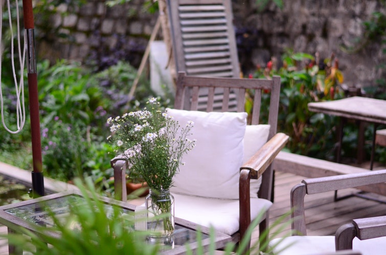 Patio à la décoration champêtre avec des meubles patinés et des fleurs des champs